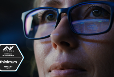 A close up of a person wearing glasses and looking away with a six-sided badge that reads: FF Awards Artificial Intelligence and thinktum with finalist 2022.